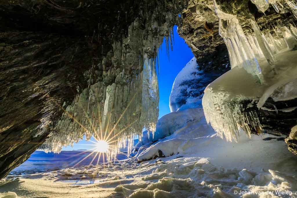 View from the ice cave...made during the Arctic Aurora Chase 2019 #aac2019After a spectacular night on the lake Torneträsk near Abisko with dancing auroras and the special pink ribbon, the next day the whole day began to get cloudy and cold. After a picture with pink shiny mountains we found this ice cave on the shore of the frozen lake, completely covered with icicles. It was hard to crawl in without breaking the ice or scratching yourself but finally I managed to find a spot where I could let the rising sun peaking throgh the icicles.regards, Johan van der Wielen