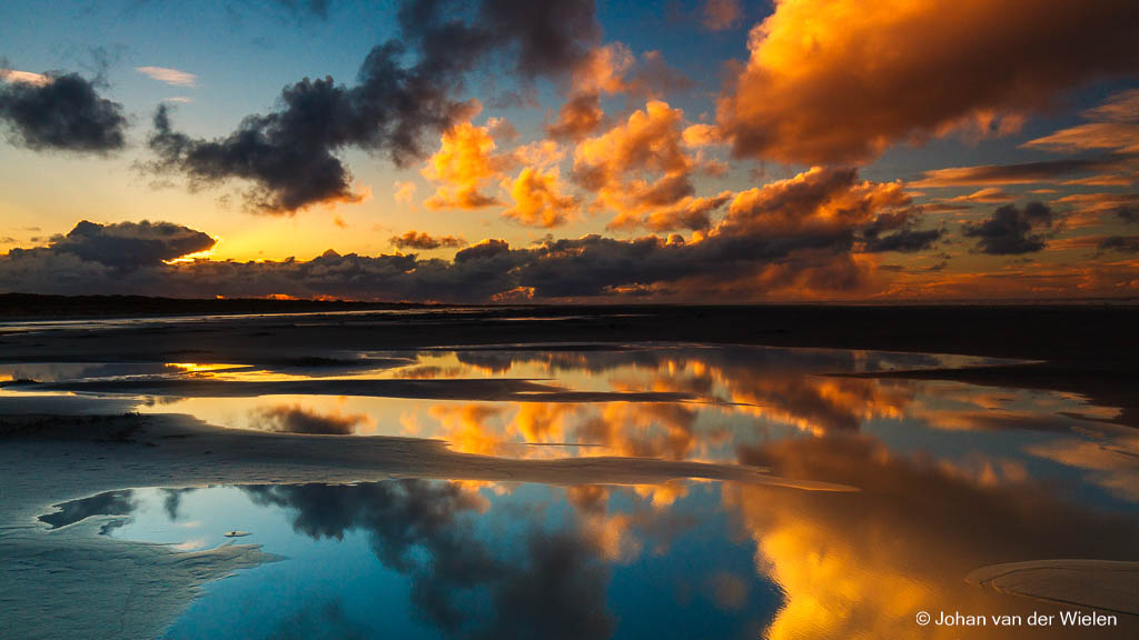 reflecties van wolken in het natte zand