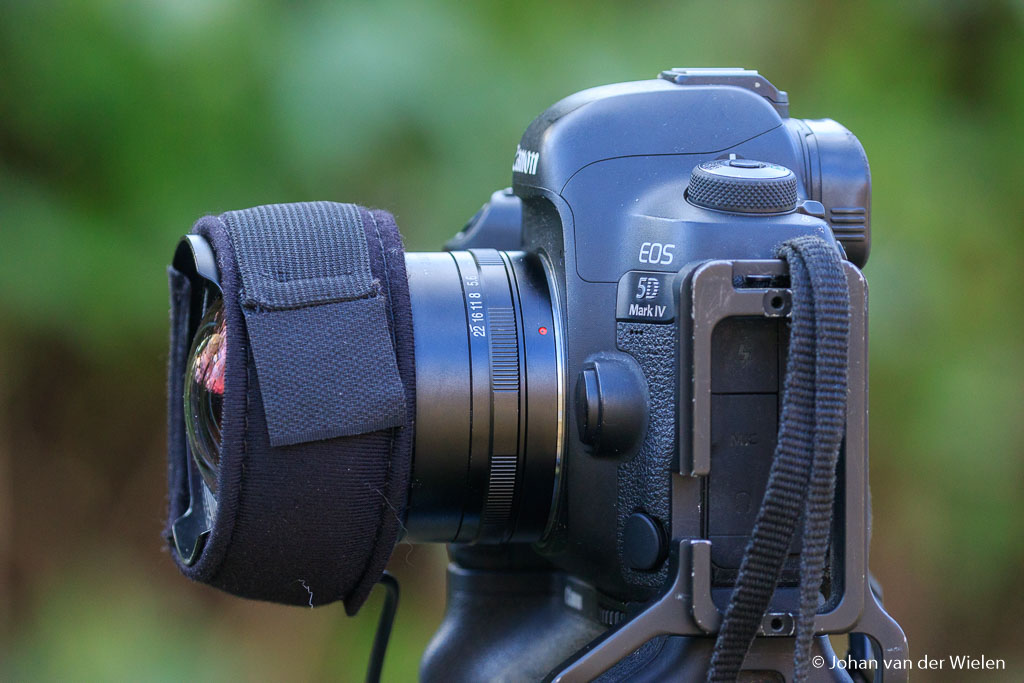 Dauwlint om de lens heen. Hoe verder naar voren gemonteerd hoe beter hij het frontelement warm houdt, maar let op dat je geen vignettering krijgt!